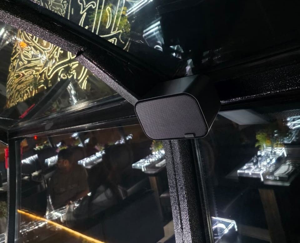Artsound UNI20 on-wall speaker mounted discreetly in the corner of a restaurant bus window frame