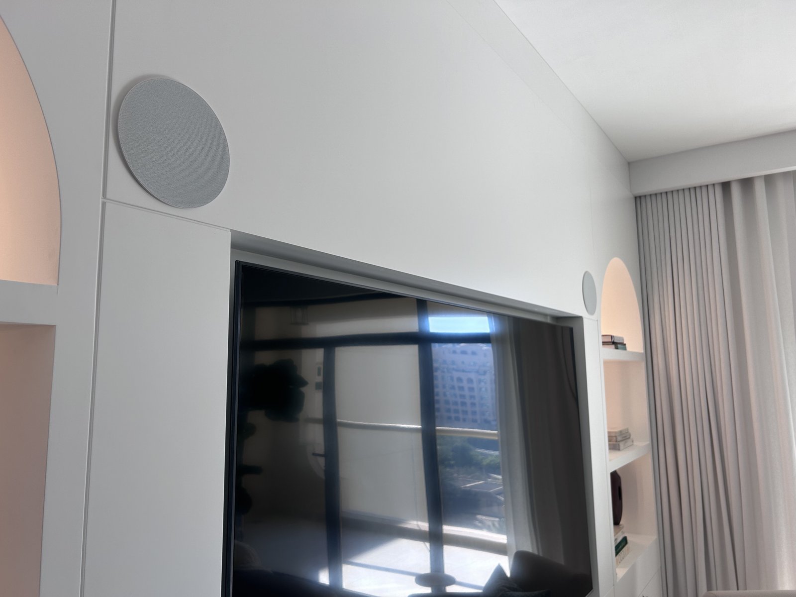 Two Artsound on-wall speakers flanking a TV as front channels in a home cinema setup