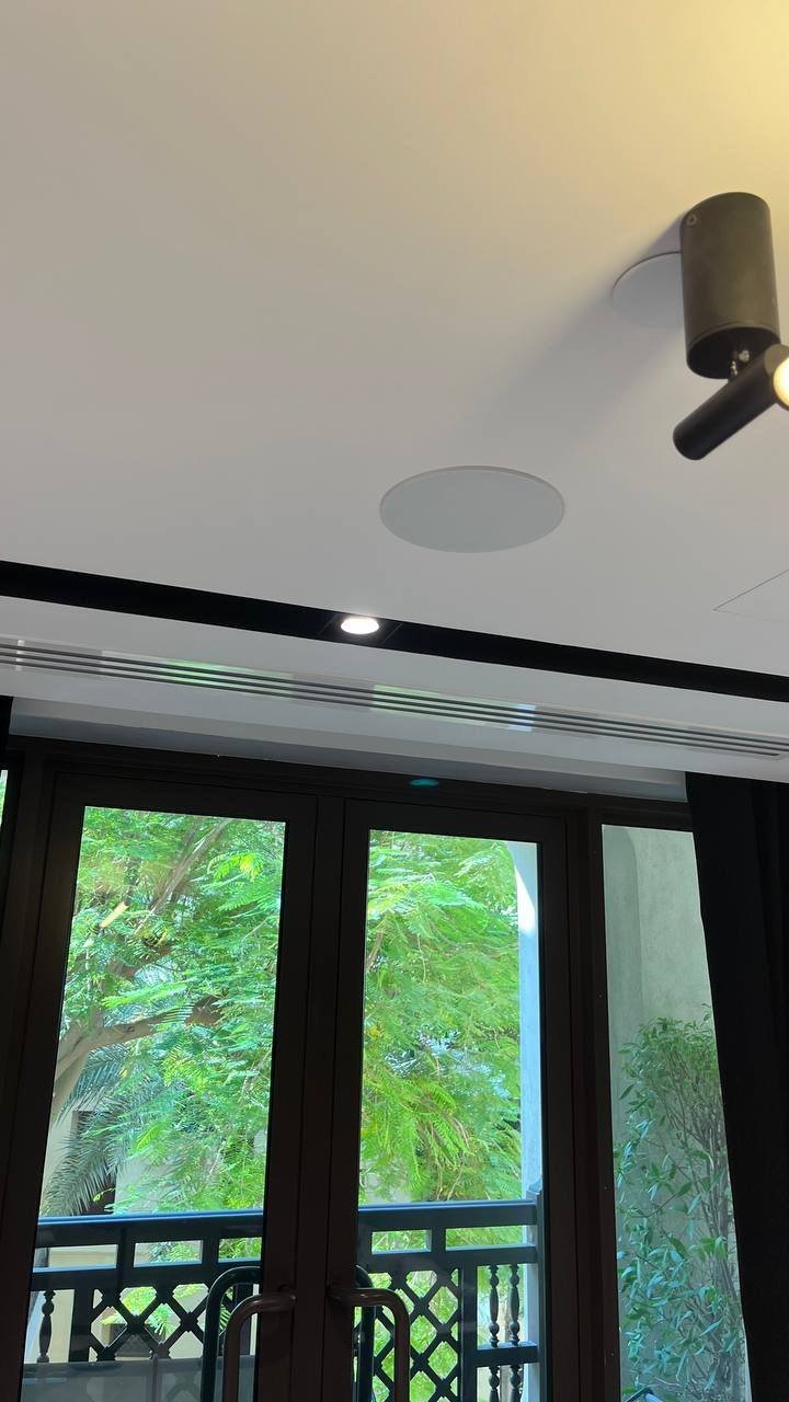 In-ceiling speaker on an office balcony ceiling with spotlight and greenery